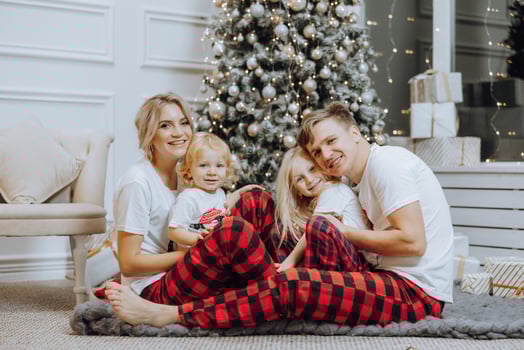 Cheerful and happy family with Christmas gifts near the Christmas tree in matching pajamas. Children are having fun. Loving family with gifts in the room. photo