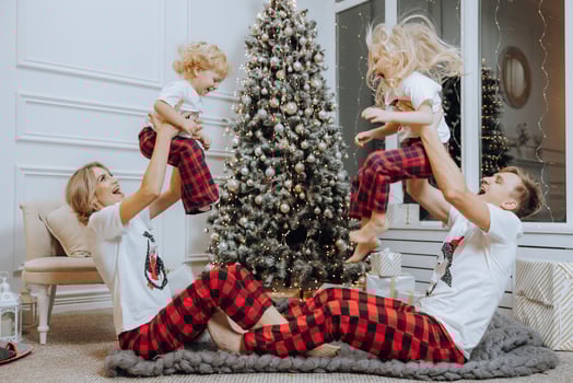 Cheerful and happy family with Christmas gifts near the Christmas tree in matching pajamas. Children are having fun. Loving family with gifts in the room. photo