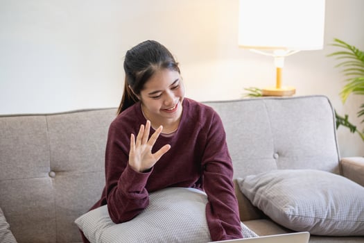 Relaxed young Asian woman enjoying relaxation on a comfy sofa at home. The beautiful girl calmly relaxes and breathes fresh air in the house. Watch movies and social networks. photo