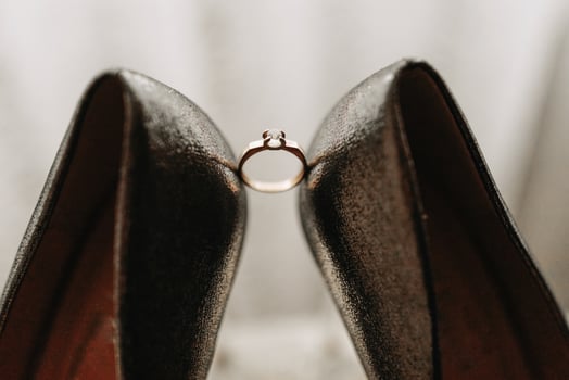 elegant gold wedding ring with diamond on a white background, between women's shoes photo