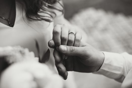 The groom holds the bride's hand. Young couple in nature. A beautiful wedding ring on the finger of the virgin. Black and white photo