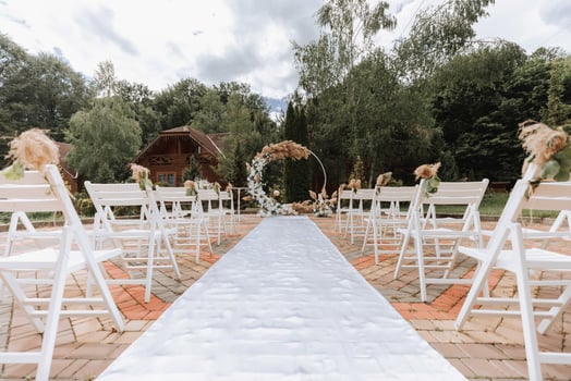 The wedding arch in the park is made of fresh flowers and dry reeds. Away wedding ceremony. White chairs for the ceremony photo