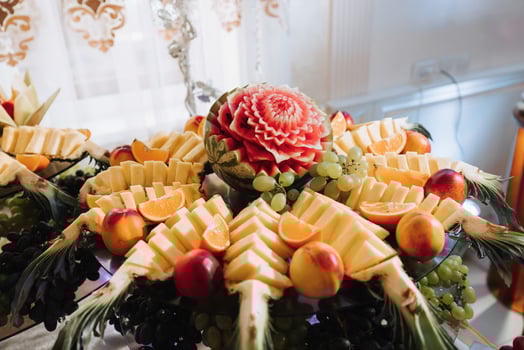 table with various fruit decorations. Watermelon carving, pineapple slices, grapes, orange photo