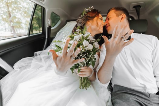 young happy bride and groom are rejoicing after the wedding ceremony in their car photo