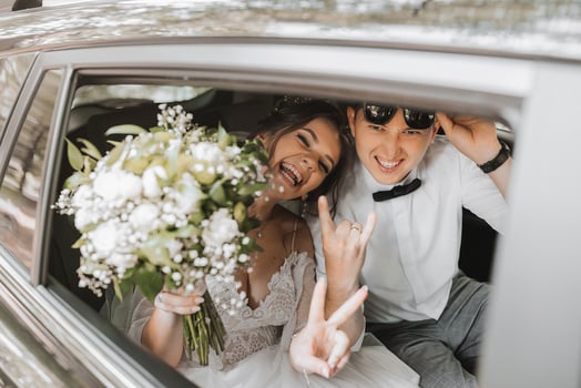 young happy bride and groom are rejoicing after the wedding ceremony in their car photo