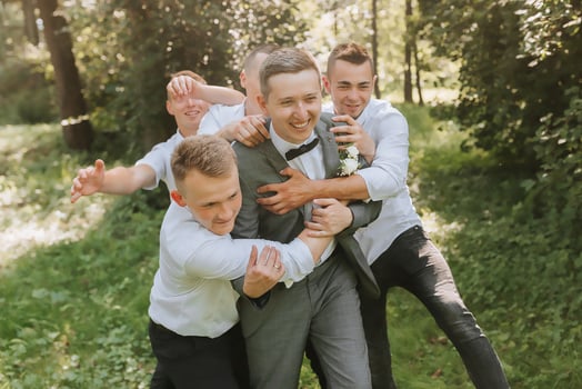 The groom celebrates his wedding with friends outdoors after the ceremony photo