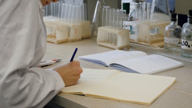 Young scientist doctor taking notes. Female scientist takes notes in the background are the tubes photo
