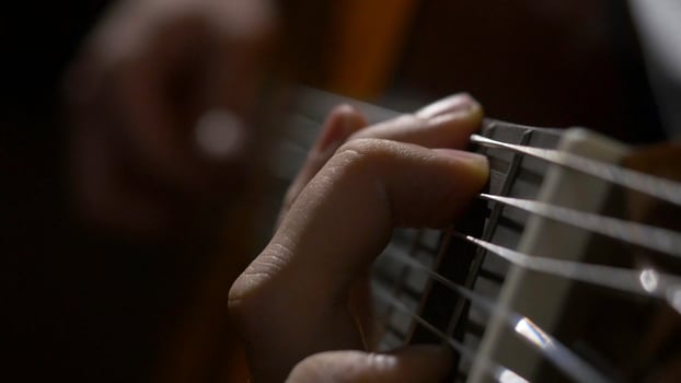 Close up of guitarist hand playing acoustic guitar. Close up shot of a man with his fingers on the frets of a guitar playing photo