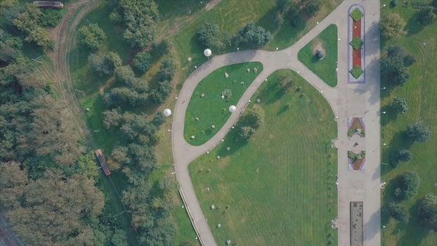 Descend on green park in city and birds flying away. Clip. Top video footage of park with green landscape and plantation on side of railway photo