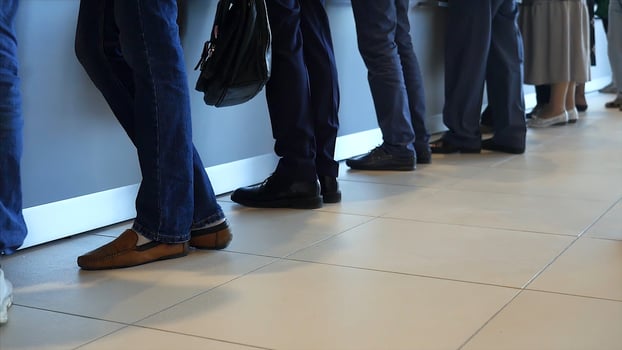 View of legs of customers standing n the modern office, getting served in the bank. Media. People are queuing for service in the department of a bank. photo