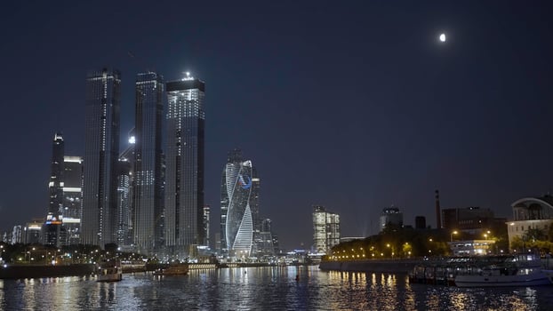Moscow 2021. Action. Beautiful huge evening buildings near the river in Moscow were shot from afar on a dark evening with bright lights and lanterns that glow . photo