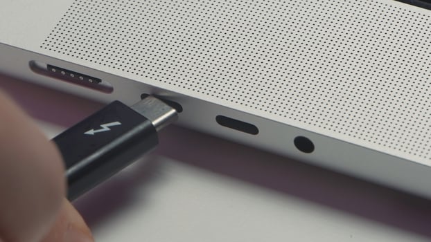 Close-up of charging wire inserted into laptop. Action. Charging your phone via laptop. Phone charging cable is connected to laptop input photo
