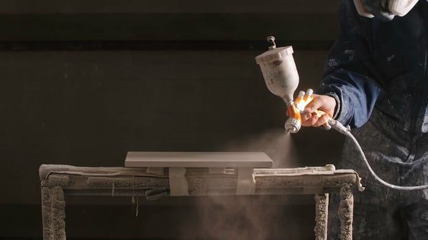 Delhi, India - April 29, 2023. Close-up of man spray painting board in workshop. Creative. Epic painting of board in workshop. Professional spray painting of objects in workshop photo