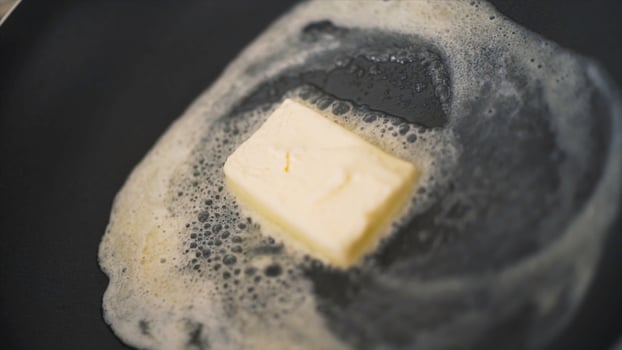 Close-up of piece of butter melting in frying pan. Action. Cooking dish in frying pan with melted piece of butter. Fat butter melts in hot pan photo
