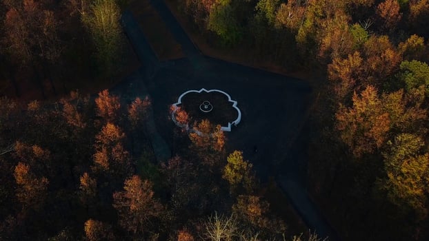 Top view of fountain and roads in autumn forest. Clip. Roads intersect in center with fountain. Crossroads with fountain in autumn forest on cloudy day photo