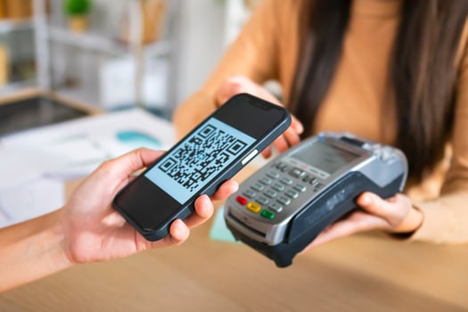 Young Asian woman smiling and paying with smartphone in restaurant photo