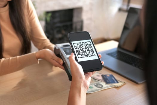 Young Asian woman smiling and paying with smartphone in restaurant photo