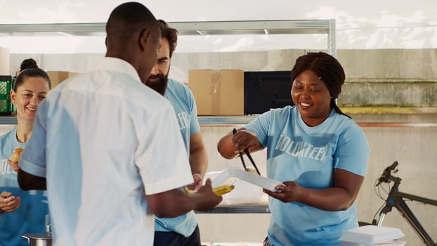 Volunteers sharing free food and other necessities to the hungry and less privileged. Friendly humanitarians donate meals and provide assistance to the poor and homeless people. Tripod shot. photo