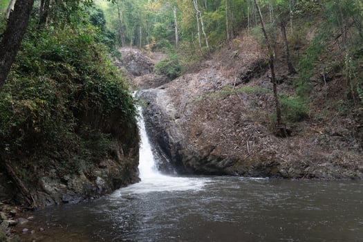 Chae Son waterfall flowing down a steep rocky hill. First level waterfall. Shallow pools and rocks, surrounded by lush green forests. At Chae Son National Park Thailand. photo