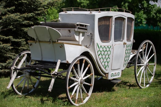 An antique white carriage from the nineteenth century on a green lawn. The prototype of a modern car. photo