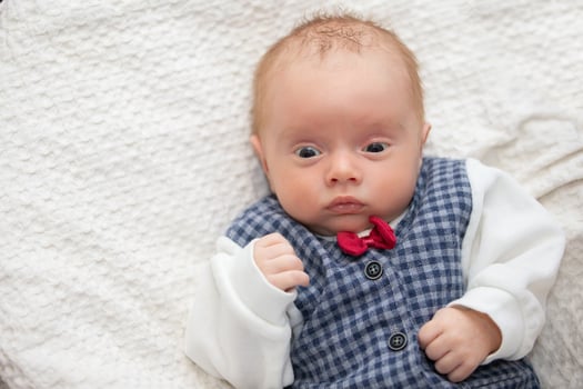 Portrait of a newborn baby wearing an elegant vest with a red bow tie. photo