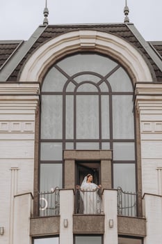 bride on the balcony of the hotel in a white robe with a veil, free space, vertical photo. On your wedding day photo