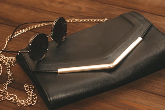 Black clutch bag with chain and iron-rimmed glasses. photo