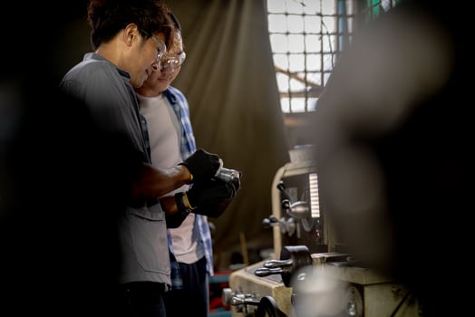 Men are inspecting steel parts for machine installation. team of teacher and student are learning to use heavy machines in steel factory. workers cooperate while doing quality control of manufactured. photo