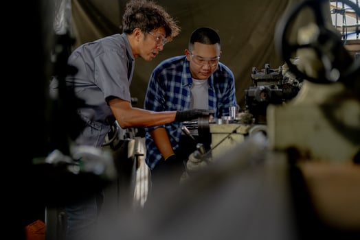 Men are inspecting steel parts for machine installation. team of teacher and student are learning to use heavy machines in steel factory. workers cooperate while doing quality control of manufactured. photo
