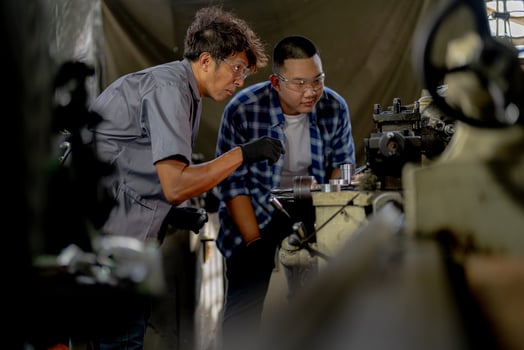 Men are inspecting steel parts for machine installation. team of teacher and student are learning to use heavy machines in steel factory. workers cooperate while doing quality control of manufactured. photo