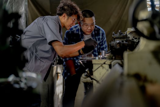 Men are inspecting steel parts for machine installation. team of teacher and student are learning to use heavy machines in steel factory. workers cooperate while doing quality control of manufactured. photo