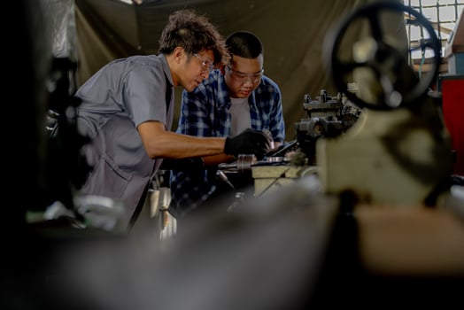Men are inspecting steel parts for machine installation. team of teacher and student are learning to use heavy machines in steel factory. workers cooperate while doing quality control of manufactured. photo