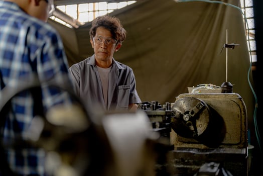 Men are inspecting steel parts for machine installation. team of teacher and student are learning to use heavy machines in steel factory. workers cooperate while doing quality control of manufactured. photo