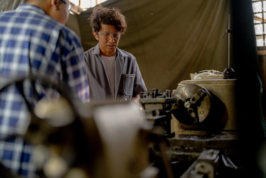 Men are inspecting steel parts for machine installation. team of teacher and student are learning to use heavy machines in steel factory. workers cooperate while doing quality control of manufactured. photo
