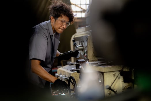 Asian worker in production plant drilling at machine. Professional worker near drilling machine on factory. finishing metal working internal steel surface on lathe grinder machine with flying sparks. photo