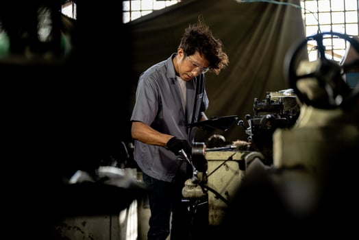 Asian worker in production plant drilling at machine. Professional worker near drilling machine on factory. finishing metal working internal steel surface on lathe grinder machine with flying sparks. photo