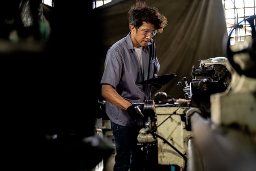 Asian worker in production plant drilling at machine. Professional worker near drilling machine on factory. finishing metal working internal steel surface on lathe grinder machine with flying sparks. photo