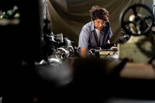 Asian worker in production plant drilling at machine. Professional worker near drilling machine on factory. finishing metal working internal steel surface on lathe grinder machine with flying sparks. photo