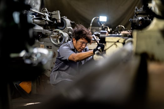 Asian worker in production plant drilling at machine. Professional worker near drilling machine on factory. finishing metal working internal steel surface on lathe grinder machine with flying sparks. photo