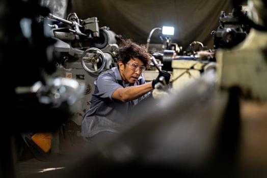 Asian worker in production plant drilling at machine. Professional worker near drilling machine on factory. finishing metal working internal steel surface on lathe grinder machine with flying sparks. photo