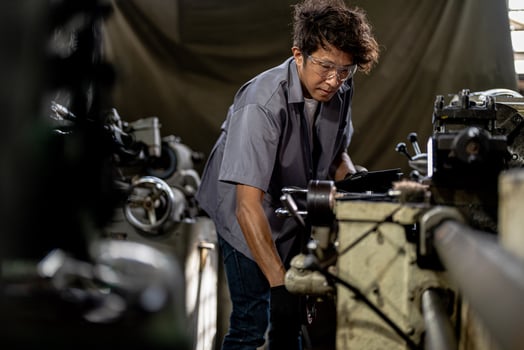 Asian worker in production plant drilling at machine. Professional worker near drilling machine on factory. finishing metal working internal steel surface on lathe grinder machine with flying sparks. photo