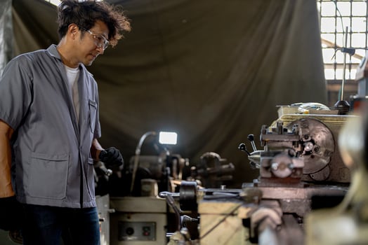 Asian worker in production plant drilling at machine. Professional worker near drilling machine on factory. finishing metal working internal steel surface on lathe grinder machine with flying sparks. photo