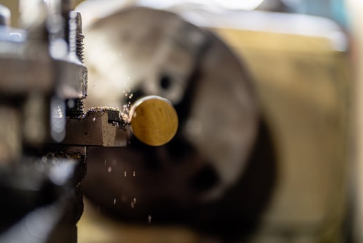 The operation of a metal lathe is captured in detail, featuring a steel column rolling during precision machining. photo