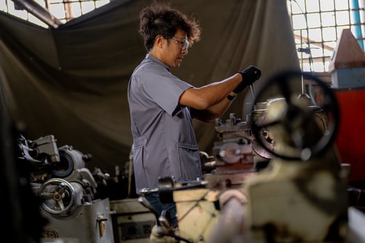 Asian worker in production plant drilling at machine. Professional worker near drilling machine on factory. finishing metal working internal steel surface on lathe grinder machine with flying sparks. photo