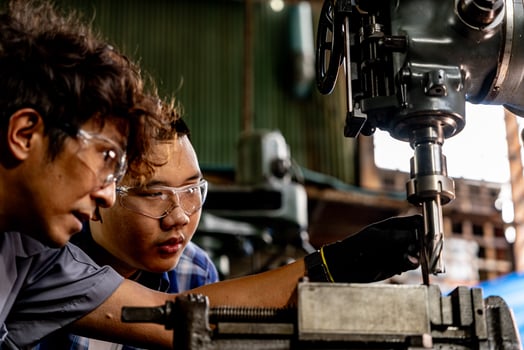 Asian worker in production plant drilling at machine. Professional worker near drilling machine on factory. finishing metal working internal steel surface on lathe grinder machine with flying sparks. photo