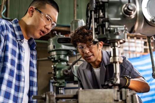 Asian worker in production plant drilling at machine. Professional worker near drilling machine on factory. finishing metal working internal steel surface on lathe grinder machine with flying sparks. photo