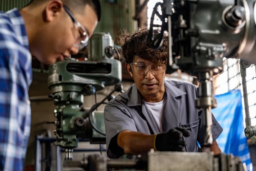 Asian worker in production plant drilling at machine. Professional worker near drilling machine on factory. finishing metal working internal steel surface on lathe grinder machine with flying sparks. photo