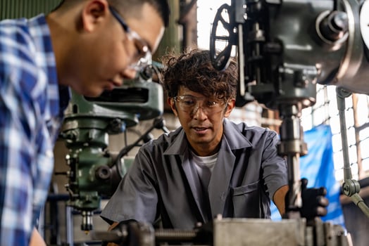 Asian worker in production plant drilling at machine. Professional worker near drilling machine on factory. finishing metal working internal steel surface on lathe grinder machine with flying sparks. photo