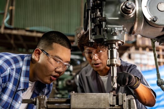 Asian worker in production plant drilling at machine. Professional worker near drilling machine on factory. finishing metal working internal steel surface on lathe grinder machine with flying sparks. photo