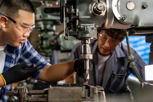 Asian worker in production plant drilling at machine. Professional worker near drilling machine on factory. finishing metal working internal steel surface on lathe grinder machine with flying sparks. photo